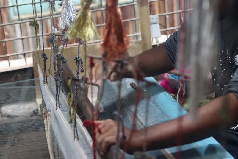 তাঁতে ঝোলানো রঙিন সুতার গুটি, তাঁতি হাতে নকশা তুলছেন