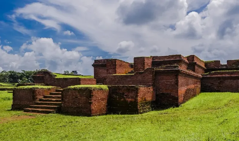 কুমিল্লার শালবন বিহারের লাল ইটের ধ্বংসাবশেষ: সিঁড়ি, কক্ষের দেয়াল আর মাঝের মন্দিরের ভিত, ওপরে মেঘলা আকাশ