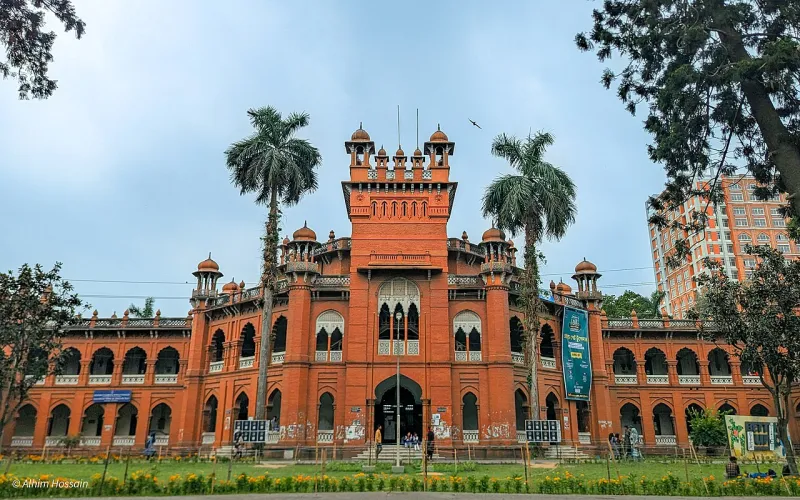 লাল ইটের কার্জন হল: মাঝখানে উঁচু মিনারসহ প্রবেশপথ, দুপাশে খিলানের সারি, সামনে সবুজ মাঠ